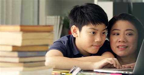 cute asian mother helping your son doing your homework at home with smile face together stock