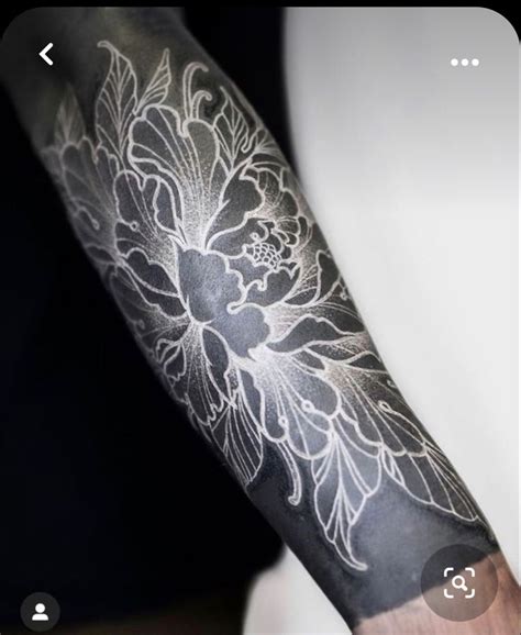 A Person With A Black And White Flower Tattoo On Their Arm