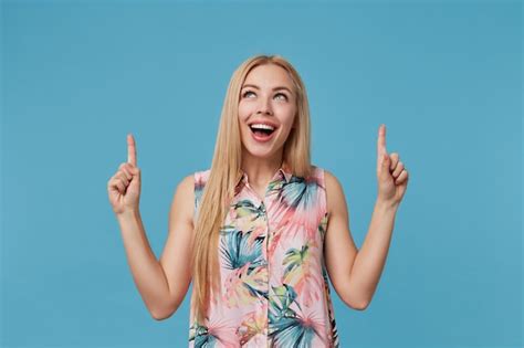 Free Photo Indoor Shot Of Positive Blonde Woman With Long Hair Pointing Upwards With Index