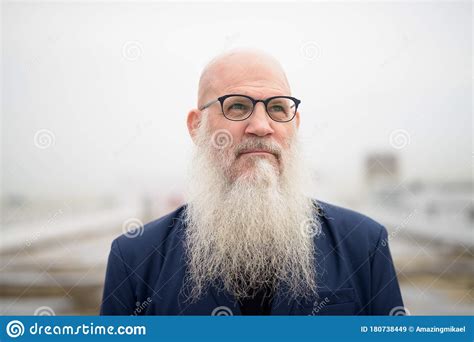 Mature Handsome Bald Bearded Businessman Thinking Against View Of The