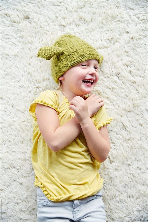 Portrait Of Cute Little Girl On Floor Giggling By Stocksy Contributor