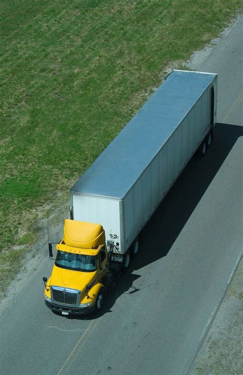 A Yellow Semi Truck Driving Down The Road