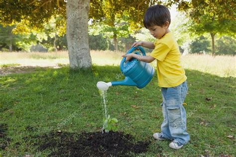 Niño Regando Una Planta Joven En El Parque — Foto De Stock