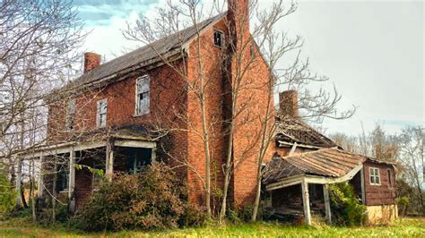 An Old Brick House Sitting In The Middle Of A Field With No Leaves On It