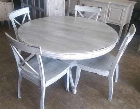 White and gray leather dining chairs sit on a gray rug around a chrome and quartz dining table lit by a rectangular chrome chandelier hung from a vaulted plank ceiling finished with skylights. Here is a 54" round table and four chairs. I painted it ...