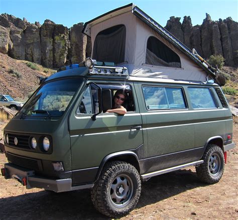 A Man Sitting In The Drivers Seat Of A Van With A Camper Attached To It