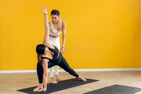 a female yoga coach controls the performance of a pose asana stretching with a trainer stock