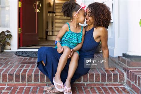 Smiling Mixed Race Mother And Daughter Rubbing Noses On Front Stoop