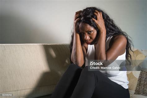 Young Attractive And Sad Black African American Woman Sitting Depressed At Home Sofa Couch
