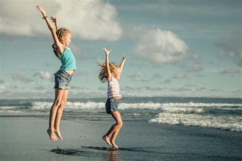 Muchachas Felices Que Saltan En La Playa Foto De Archivo Imagen De