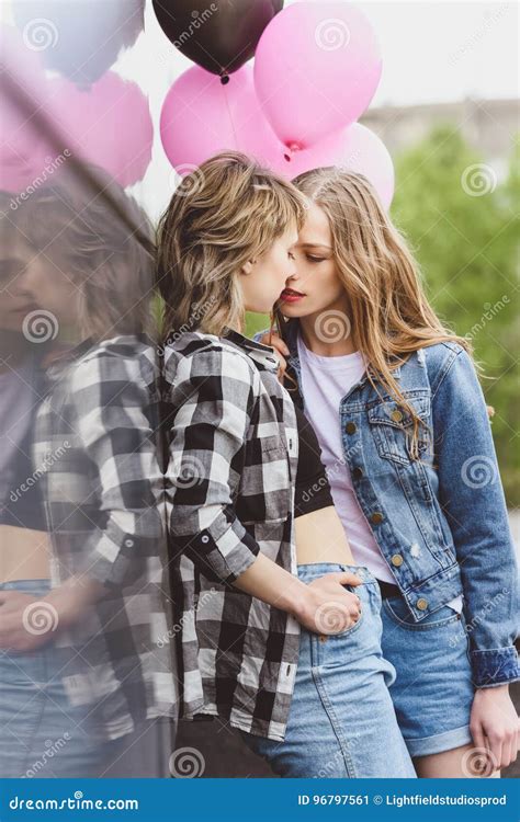casual lesbian couple kissing and holding air balloons outdoors stock image image of intimate