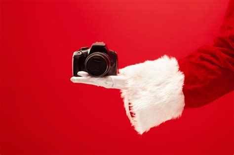 Free Photo Hand Of Santa Claus Holding A Camera On Red Background