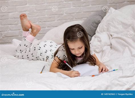 Little Girl Drawing Pictures While Lying On Bed Obraz Stock Obraz
