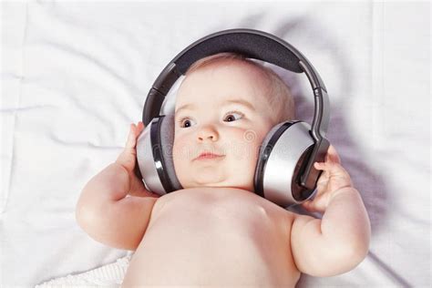 Baby Lying Down Listening To Music With Wireless Headphones Stock