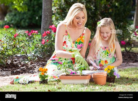 Woman And Girl Mother And Daughter Gardening Together Planting Flowers And Tomato Plants In