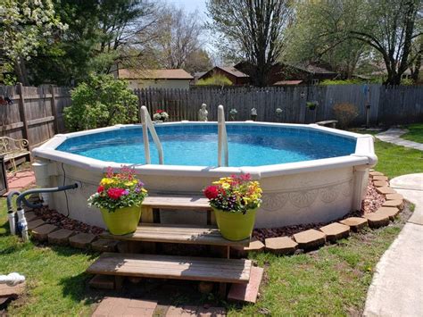 An Above Ground Pool With Steps Leading Up To It And Potted Flowers In