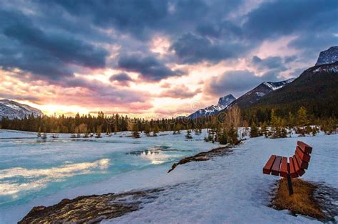 Park Bench Looking Out Over A Frozen Quarry Lake At Sunrise Stock Photo