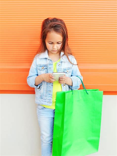 Little Girl Child With Shopping Bags Using Smartphone Stock Image