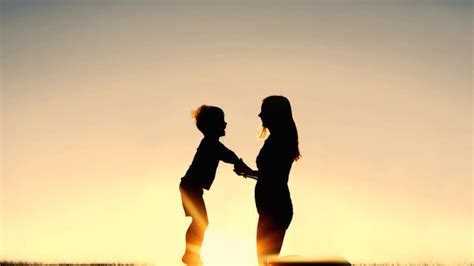 Silhouette Of Mother And Young Child Holding Hands At Sunset Big City