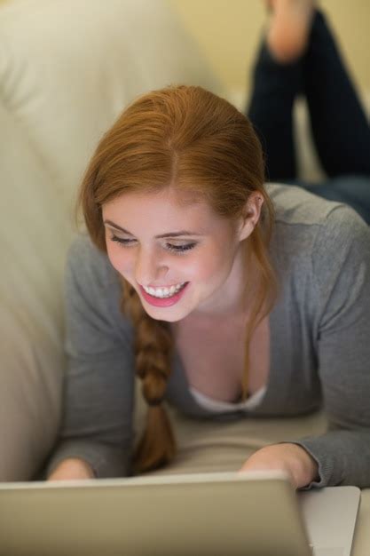 Premium Photo Smiling Redhead Lying On The Couch Using Her Laptop At
