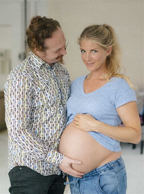 Man Touching Belly Of Smiling Pregnant Woman Stock Photo