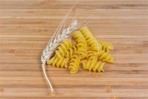 Uncooked Spiral Pasta And Wheat Ear On Wooden Surface Stock Photo