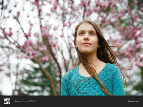 Tween Girl Standing In Front Of A Blooming Magnolia Tree