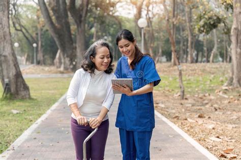 Nurse Caregiver Showing A Tablet Screen To Senior Woman And Laughing At