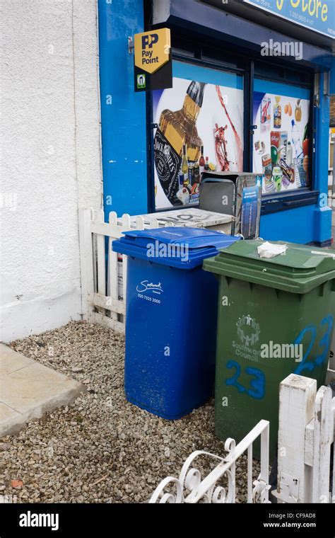 Southwark Council Wheelie Bins Within A White Fence And The Frontage Of A Corner Shop Stock