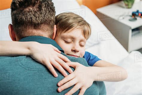 Portrait Of Little Son Hugging Father In Hospital Chamber Stock Photo