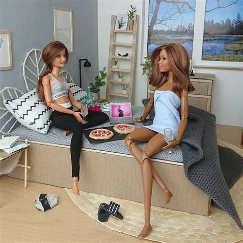 Two Barbie Dolls Sitting On A Bed With Pizza