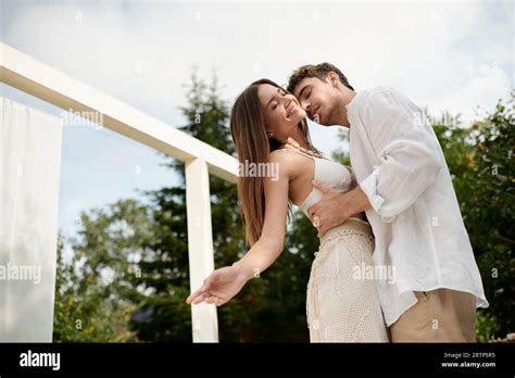 Passionate Man Embracing Cheerful Woman In White Beach Wear On Luxury