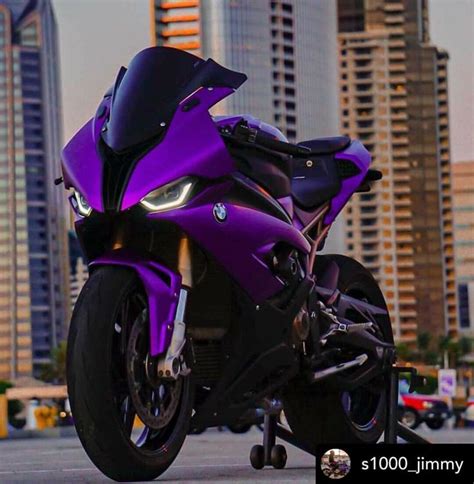 A Purple Motorcycle Parked In Front Of Tall Buildings