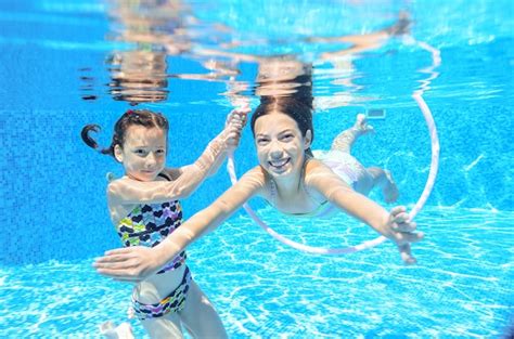 Дети плавают в бассейне под водой счастливые активные девочки