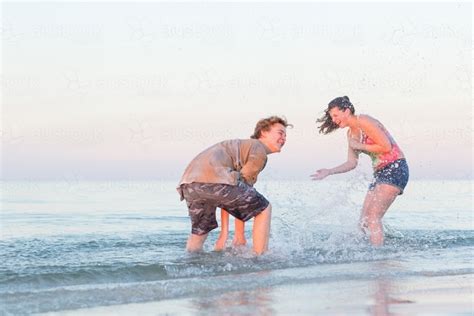 Image Of Teenage Couple Splashing Each Other At The Beach Austockphoto