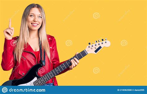 Young Beautiful Blonde Woman Playing Electric Guitar Surprised With An