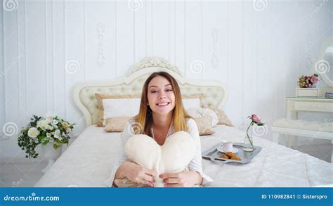 Portrait Of Cute Female Holding Pillow Heart Posing And Smiling While