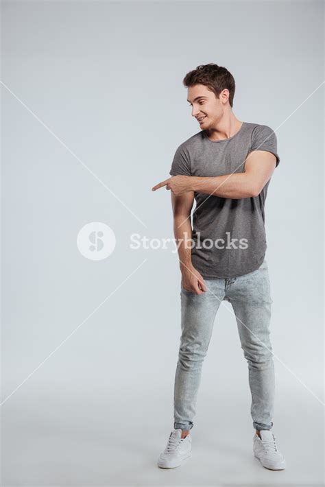 Full Length Portrait Of A Smiling Handsome Young Man Standing And