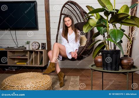 Beautiful Woman In A White Dress Sitting In The Wicker Chair At Home