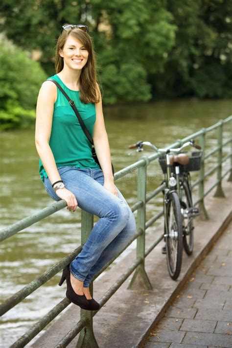 Young Woman Sitting On Railing By River Stock Image Image Of