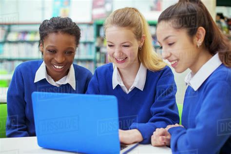 Three Smiling Female Students Wearing Blue School Uniforms Working On
