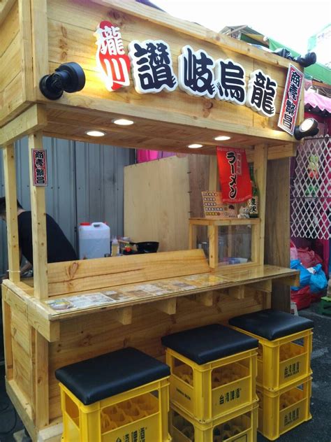 An Outdoor Food Stand With Stools In Front Of It
