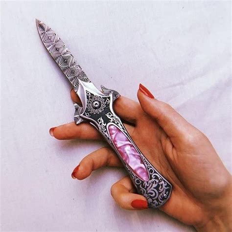 A Womans Hand Holding A Fancy Knife On A White Sheet With Black And