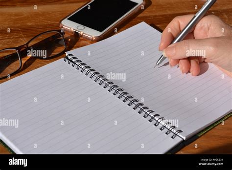 Woman With Pen In Hand Poised To Write In A Spiral Bound Notebook
