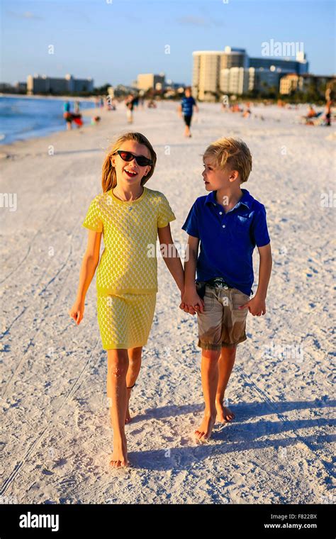 Young Pre Teen Girl And Her Brother Holding Hands As They Walk Along
