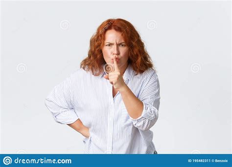 Angry And Bothered Middle Aged Redhead Woman Shushing And Frowning Press Finger To Lips Tell