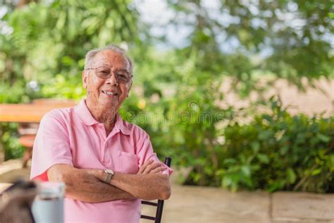 Portrait Asian Elderly Man 83 Years Old With Toothy Smile Sitting Outdoor In The Garden Stock