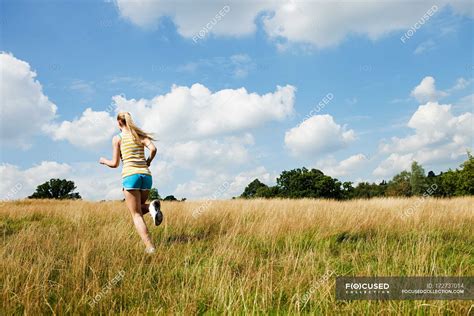 Young Woman Jogging Through A Field On A Sunny Day — Physical Training
