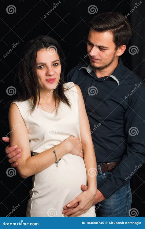 Happy Pregnant Wife And Husband Hugging On Black Background The