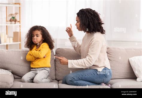 Black Mother Scolding Daughter Sitting On Sofa At Home Stock Photo Alamy